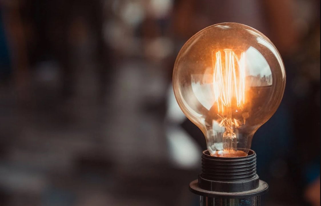 A single light bulb illuminates a hazy background to illustrate how smart lighting benefits a home.